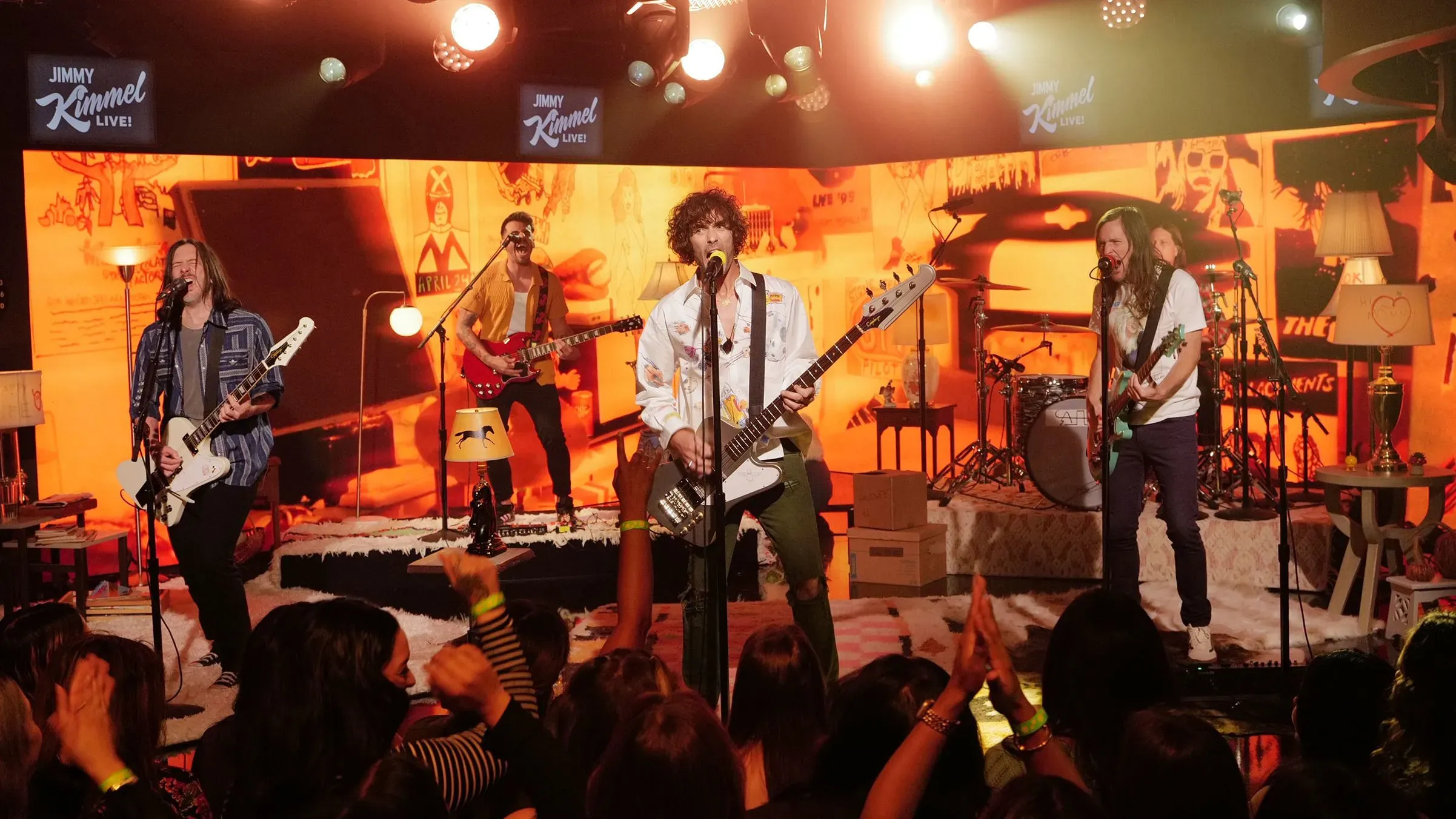 فرقة All-American Rejects تؤدي على المسرح في عرض مباشر، مع تفاعل الجمهور في خلفية مفعمة بالطاقة.