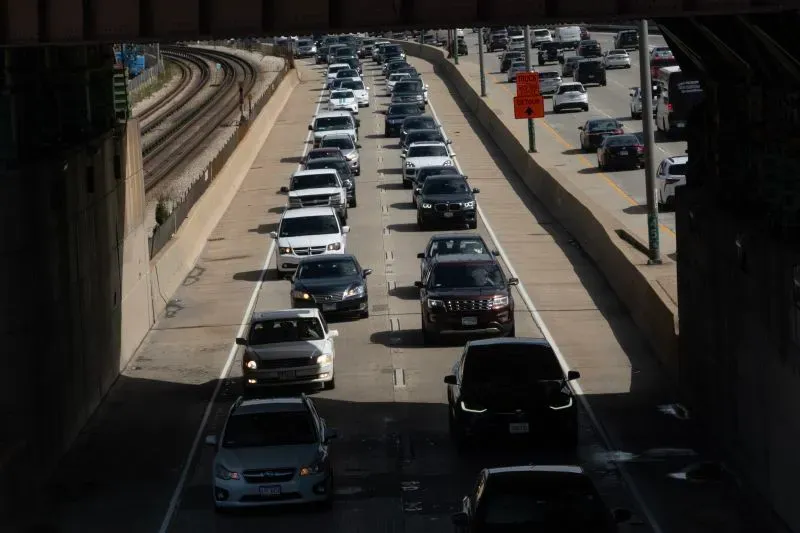 ازدحام مروري كثيف على طريق سريع، مع سيارات تسير في صفوف متقاربة تحت جسر، مما يعكس حالة عدم اليقين الاقتصادي وتأثيرها على السفر.