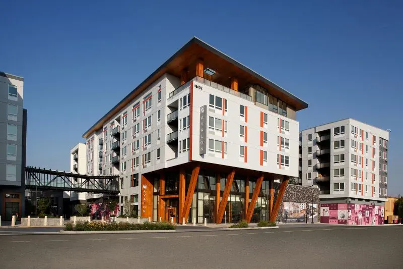 مبنى سكني حديث يتكون من عدة طوابق، مع تصميم عصري، يقع بجوار مركز تجاري متعدد الاستخدامات، يعكس تحول مراكز التسوق التقليدية.