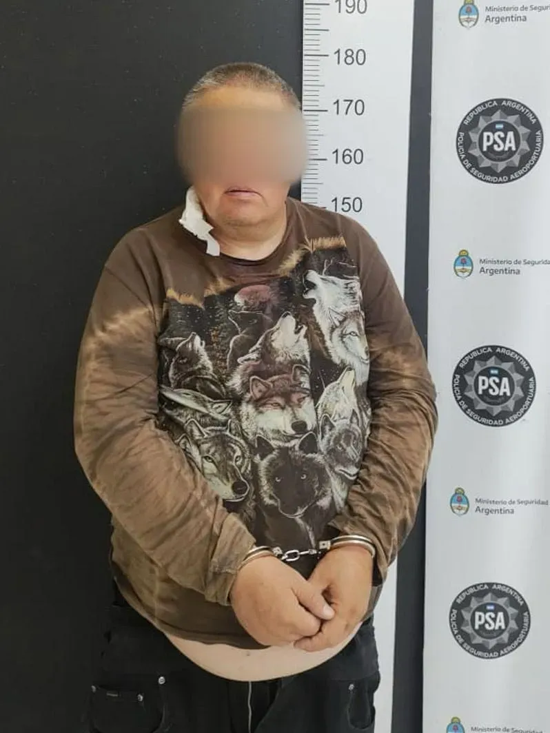 رجل محتجز يرتدي قميصًا مزخرفًا بصور ذئاب، يظهر علامات سوء التغذية، في مركز الشرطة الأرجنتينية عقب اعتقاله بتهم تتعلق بطائفة دينية.