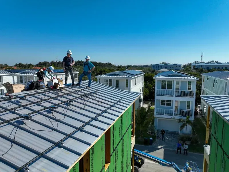 عمال يقومون بتركيب الألواح الشمسية على أسطح المنازل في مشروع سكني مبتكر في فلوريدا، يهدف إلى تعزيز المرونة في مواجهة الكوارث الطبيعية.