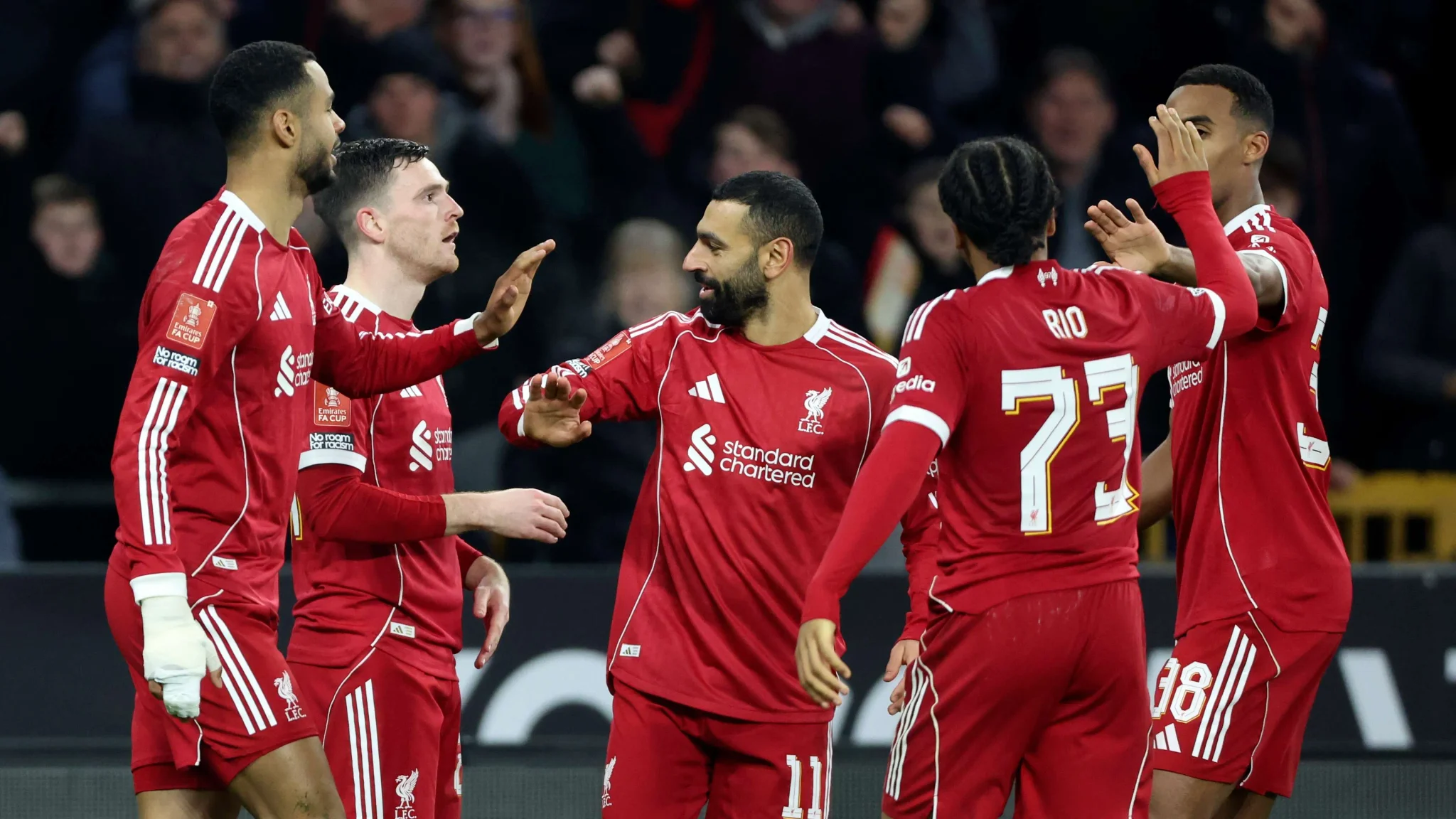 لاعبو ليفربول يحتفلون معاً خلال مباراة كرة قدم، مرتدين زي الفريق الأحمر، يعكس روح التعاون والتكاتف في الفريق.