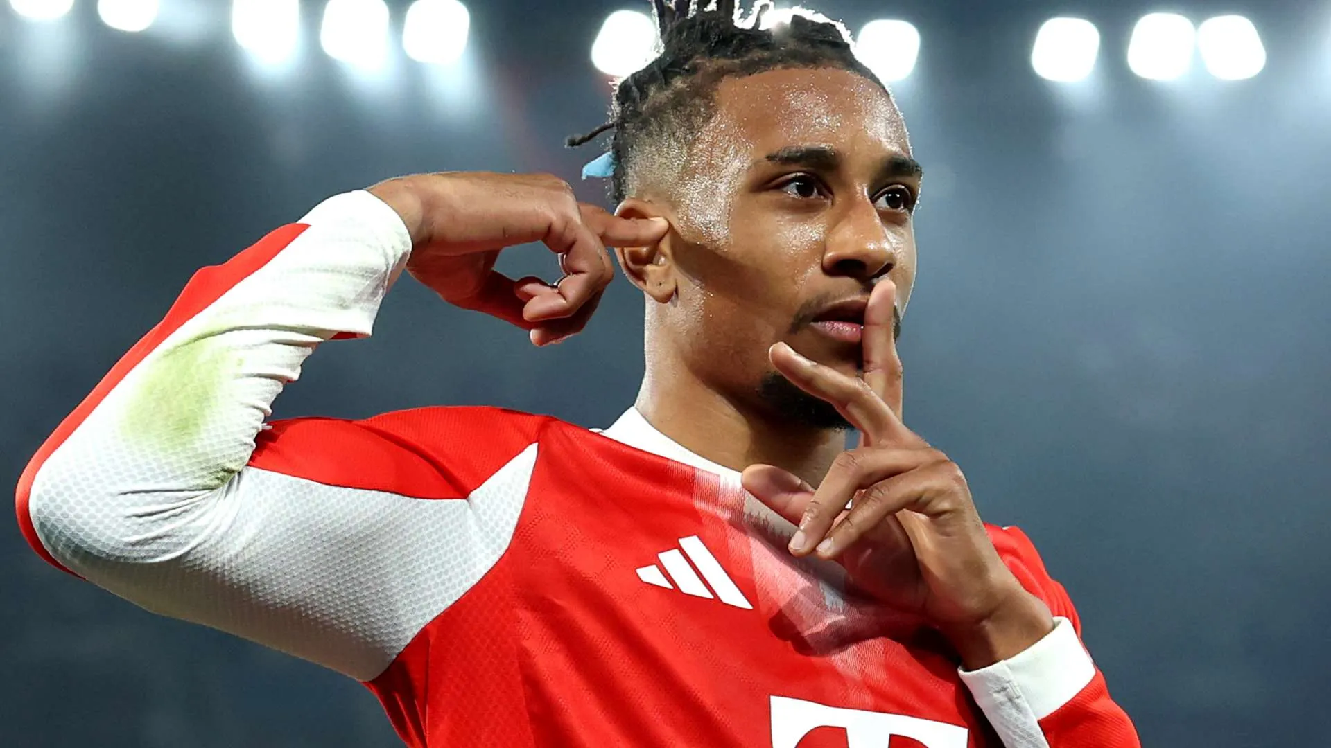 لاعب كرة قدم يرتدي زيًا أحمر وأبيض يحتفل بهدفه بإشارة صمت، يعكس لحظة حماسية في مباراة ضمن منافسات كأس العالم 2026.