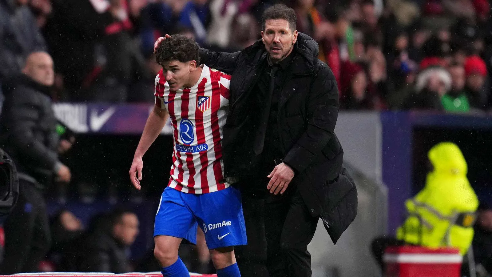 دييغو سيميوني مدرب أتلتيكو مدريد يواسي لاعب الفريق خلال مباراة في موسم 2026-2027 وسط أجواء ممطرة في الملعب.