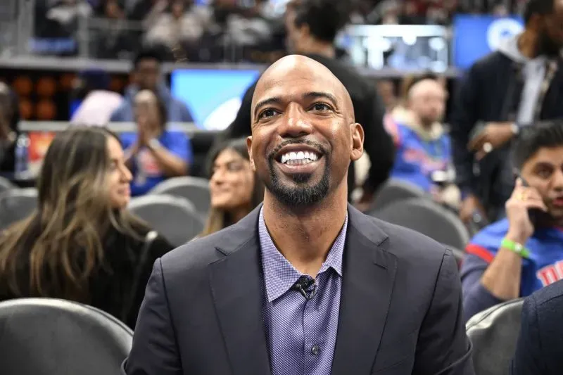 صورة لريتشارد "ريب" هاميلتون، نجم فريق ديترويت بيستونز، وهو مبتسم في المدرجات خلال مباراة. تعكس الصورة أجواء الحماس في كرة السلة.