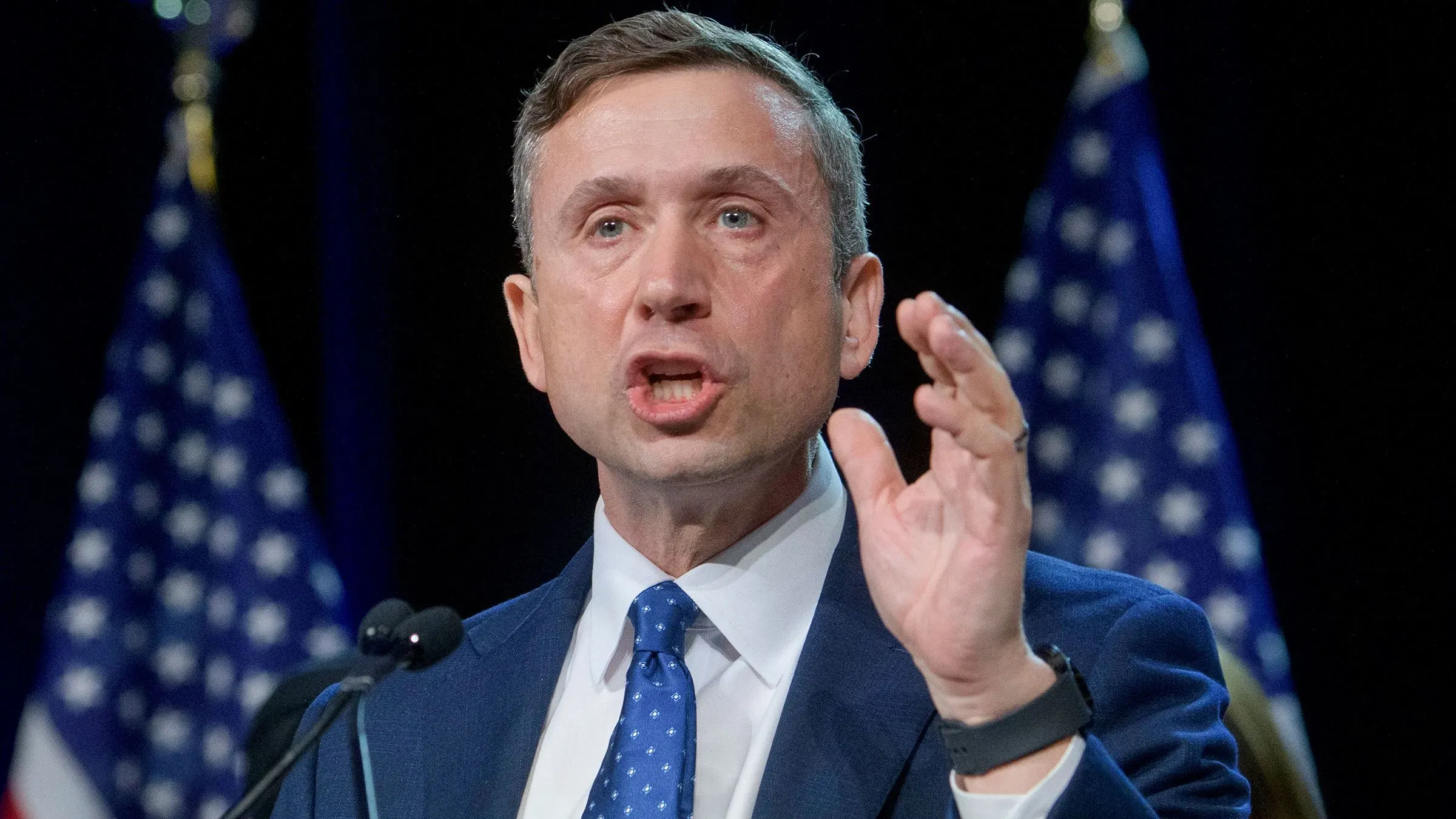 مارتن، رئيس اللجنة الوطنية الديمقراطية، يتحدث بحماس أمام الجمهور، مع وجود أعلام خلفه، وسط أجواء من التوتر السياسي.