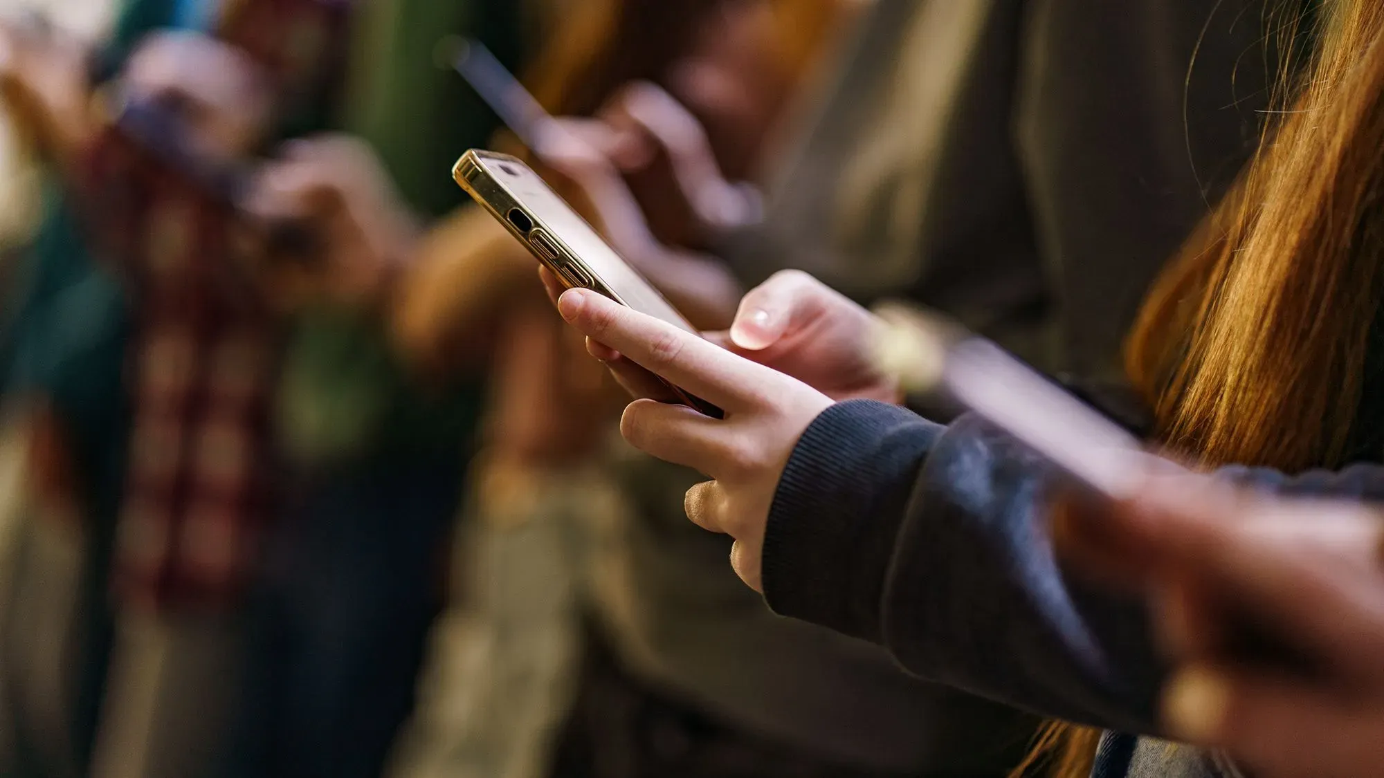 أشخاص يستخدمون هواتفهم الذكية، مما يعكس تأثير الذكاء الاصطناعي على التفاعل البشري والمهارات الأساسية.