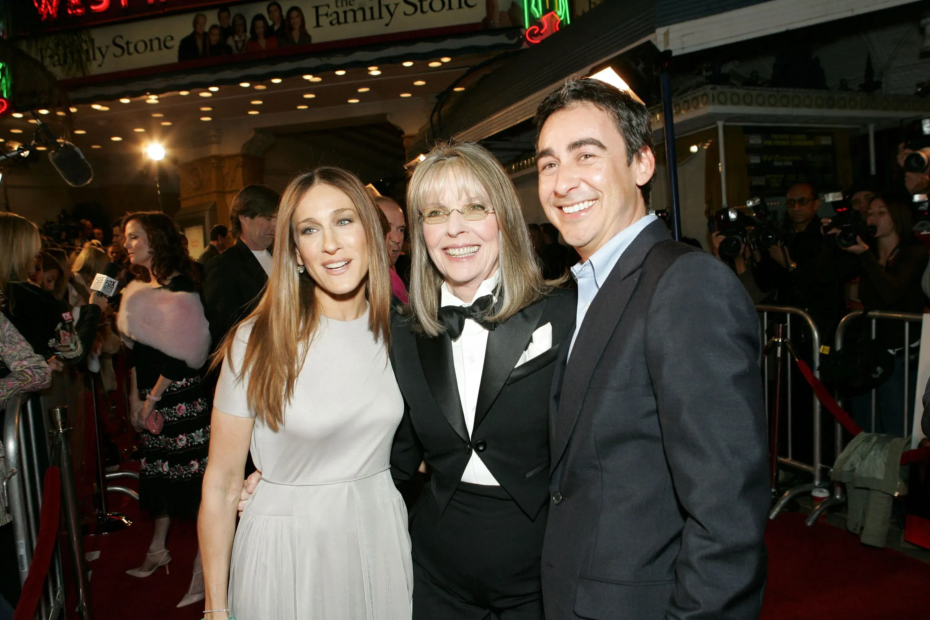 ديان كيتون تتوسط سارة جيسيكا باركر ورجل آخر في حدث خاص، مع خلفية تبرز عرض فيلم "حجر العائلة".