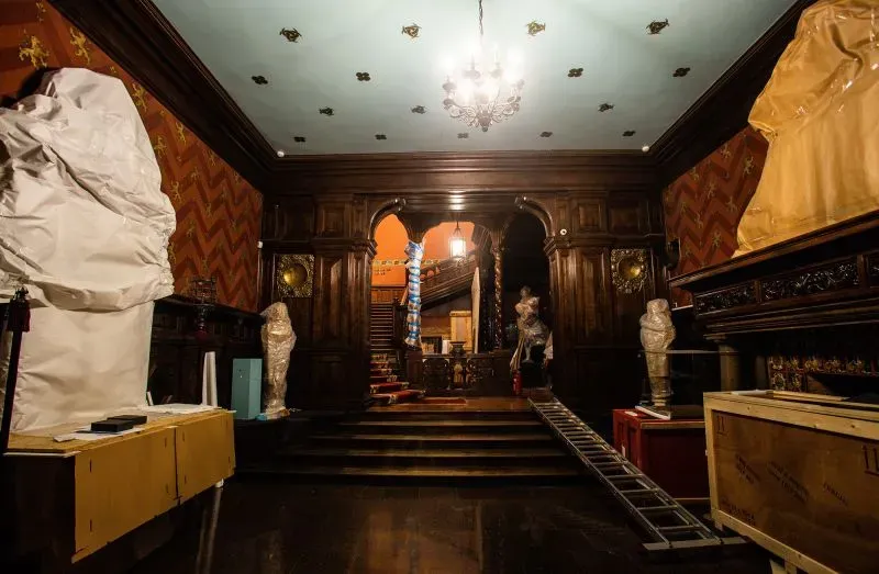 غرفة متحف تحتوي على تماثيل مغطاة بأقمشة، مع أثاث خشبي وزخارف ملونة، تعكس جهود الحفظ وسط الحرب في أوكرانيا.