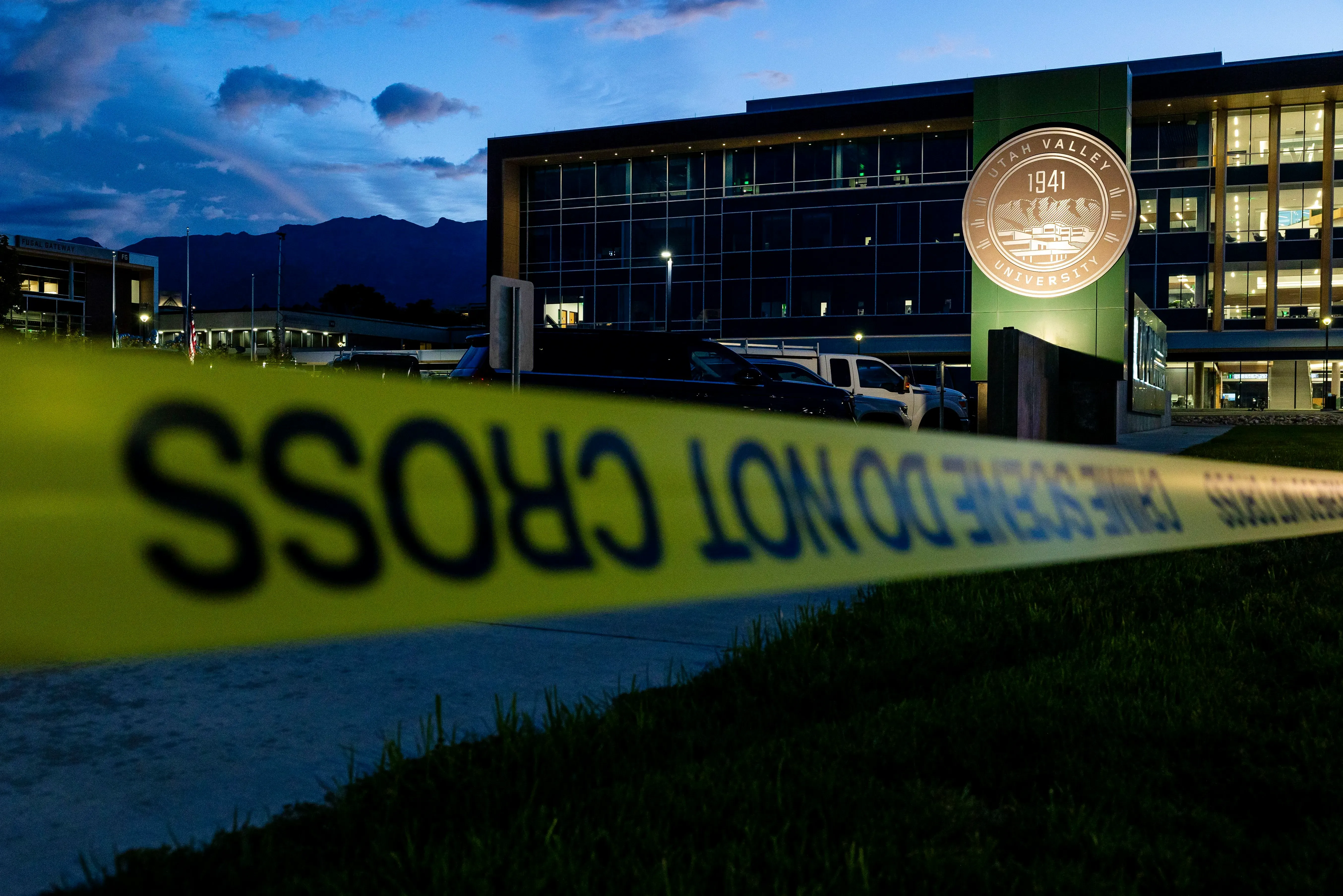 موقع جامعة يوتا فالي محاط بشريط تحذيري، مع ظهور شعار الجامعة في الخلفية، مما يشير إلى وجود تحقيقات أمنية بعد حادثة إطلاق نار.