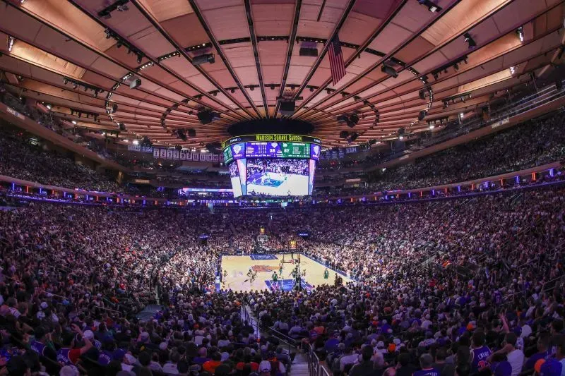 مدرج مزدحم في ماديسون سكوير غاردن خلال مباراة لكرة السلة، مع عرض النتائج على الشاشة الكبيرة، يبرز أجواء حماس مشجعي نيويورك نيكس.