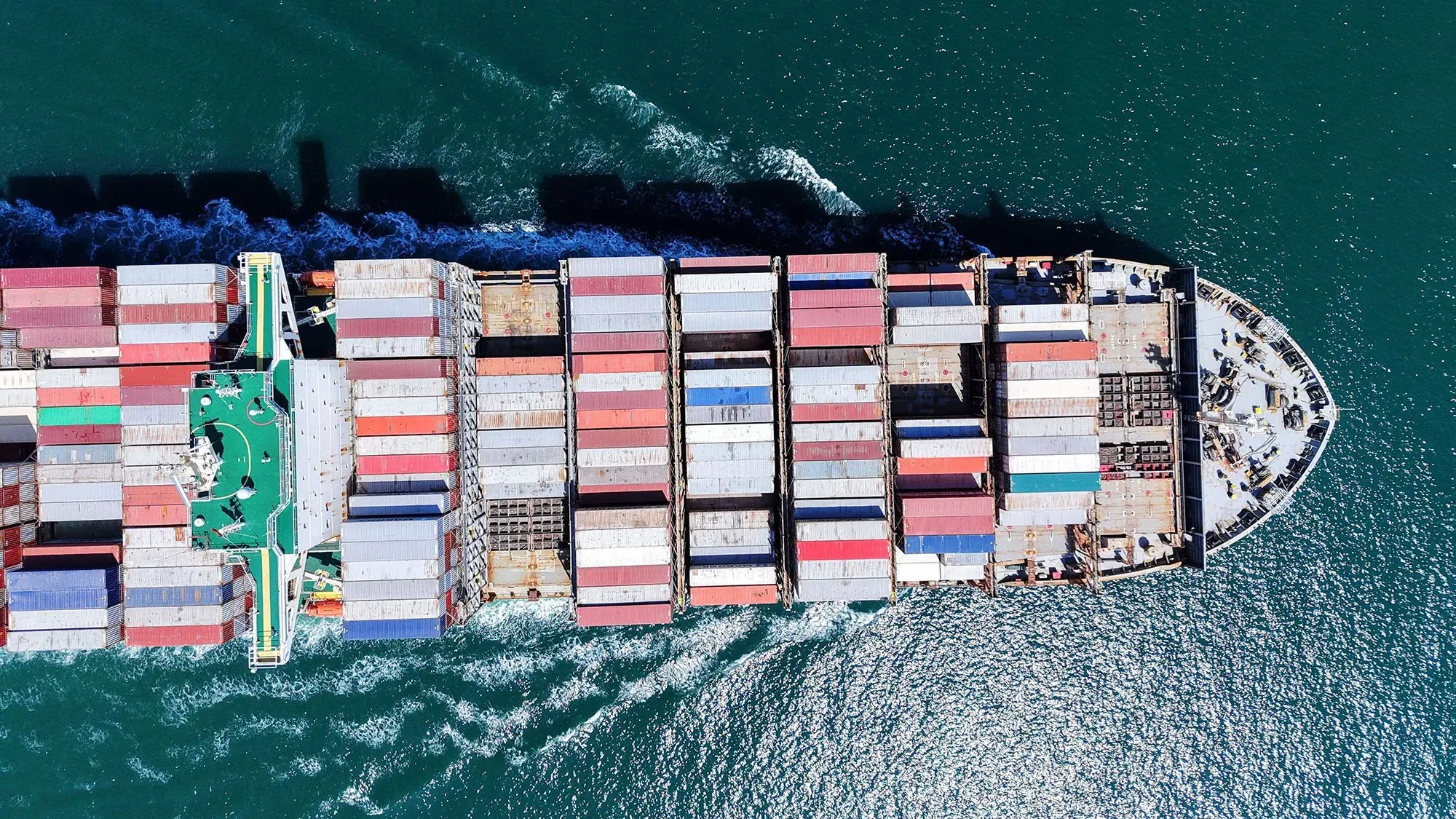 سفينة شحن كبيرة محملة بالحاويات الملونة تبحر في مياه زرقاء، تعكس تأثير التغيرات التجارية بين الصين والولايات المتحدة.