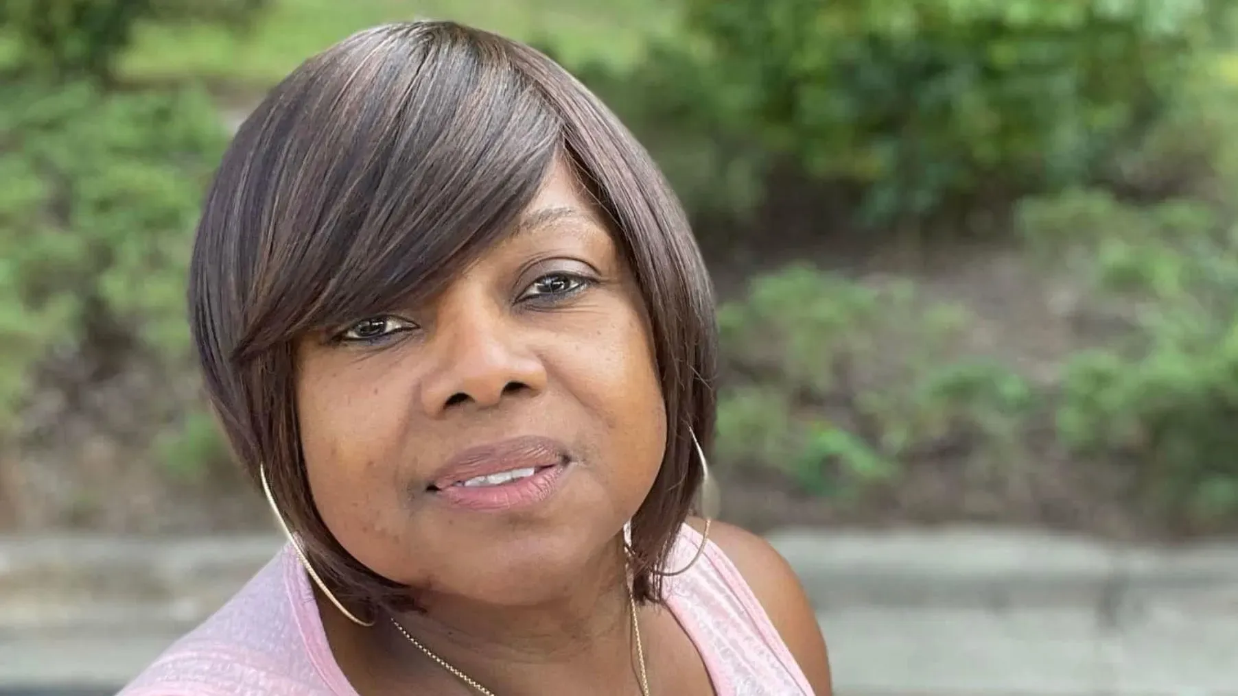 صورة لتولاند هول، امرأة ذات شعر بني قصير، تبتسم أمام خلفية خضراء، تعكس لحظات من حياتها كأم وسائقة أوبر قبل وقوع الحادث المأساوي.