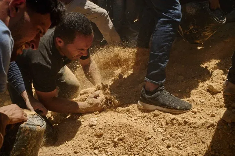 مجموعة من الرجال يعملون بجد على إزالة الأتربة في موقع حادث، وسط أجواء من الحزن والجهد، في سياق الأحداث المحيطة بمقتل سيف الله مسلط.