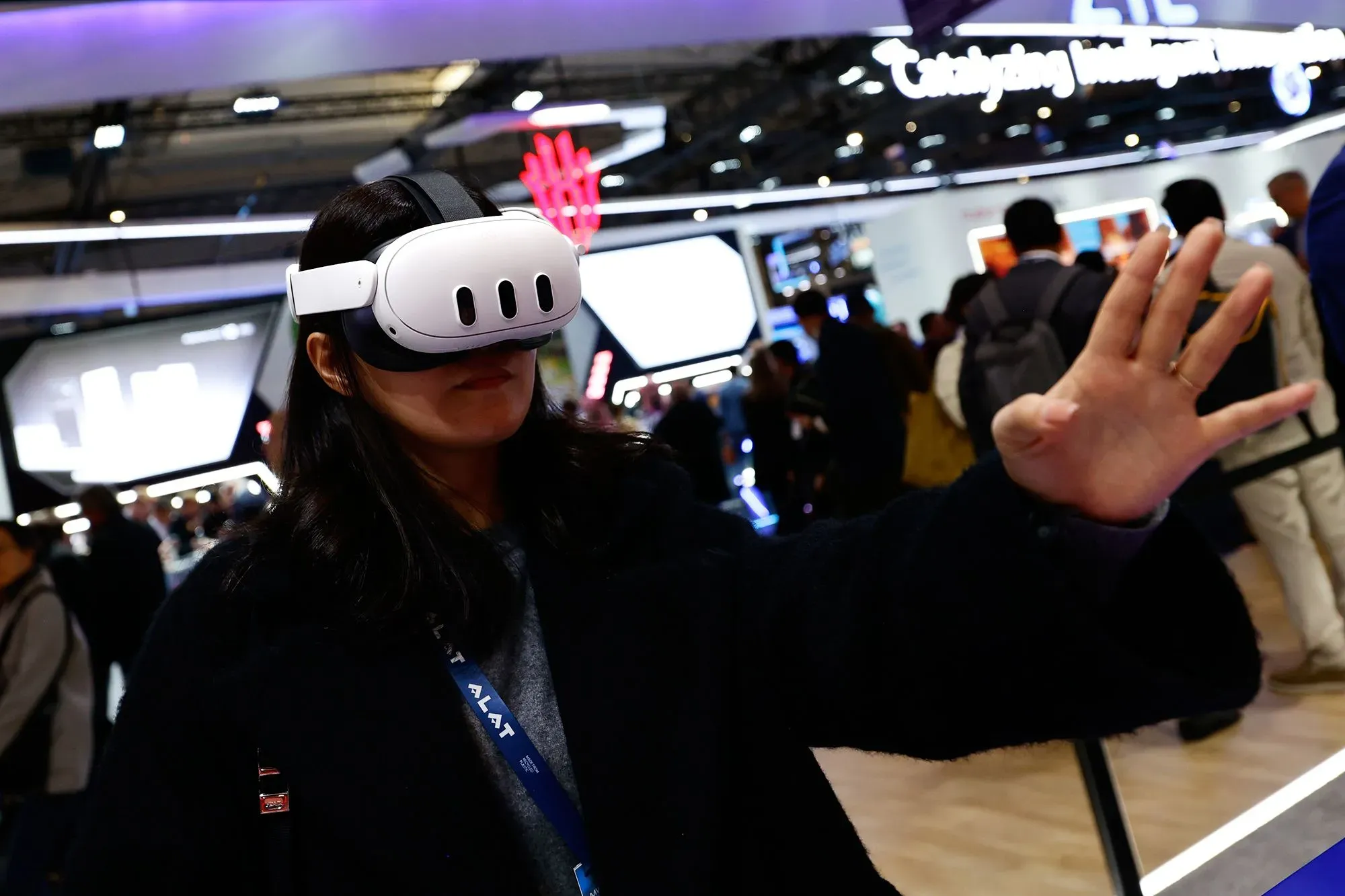 امرأة ترتدي نظارات الواقع الافتراضي، تتفاعل مع بيئة افتراضية في معرض تكنولوجي، مما يعكس توجه ميتا نحو الميتافيرس.