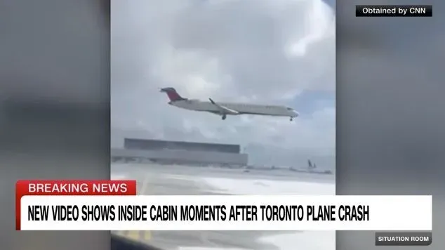 فيديو يظهر لحظات بعد تحطم طائرة دلتا في مطار تورنتو، حيث كانت الطائرة مقلوبة مع تصاعد الدخان والنيران، مما يعكس حالة الطوارئ.