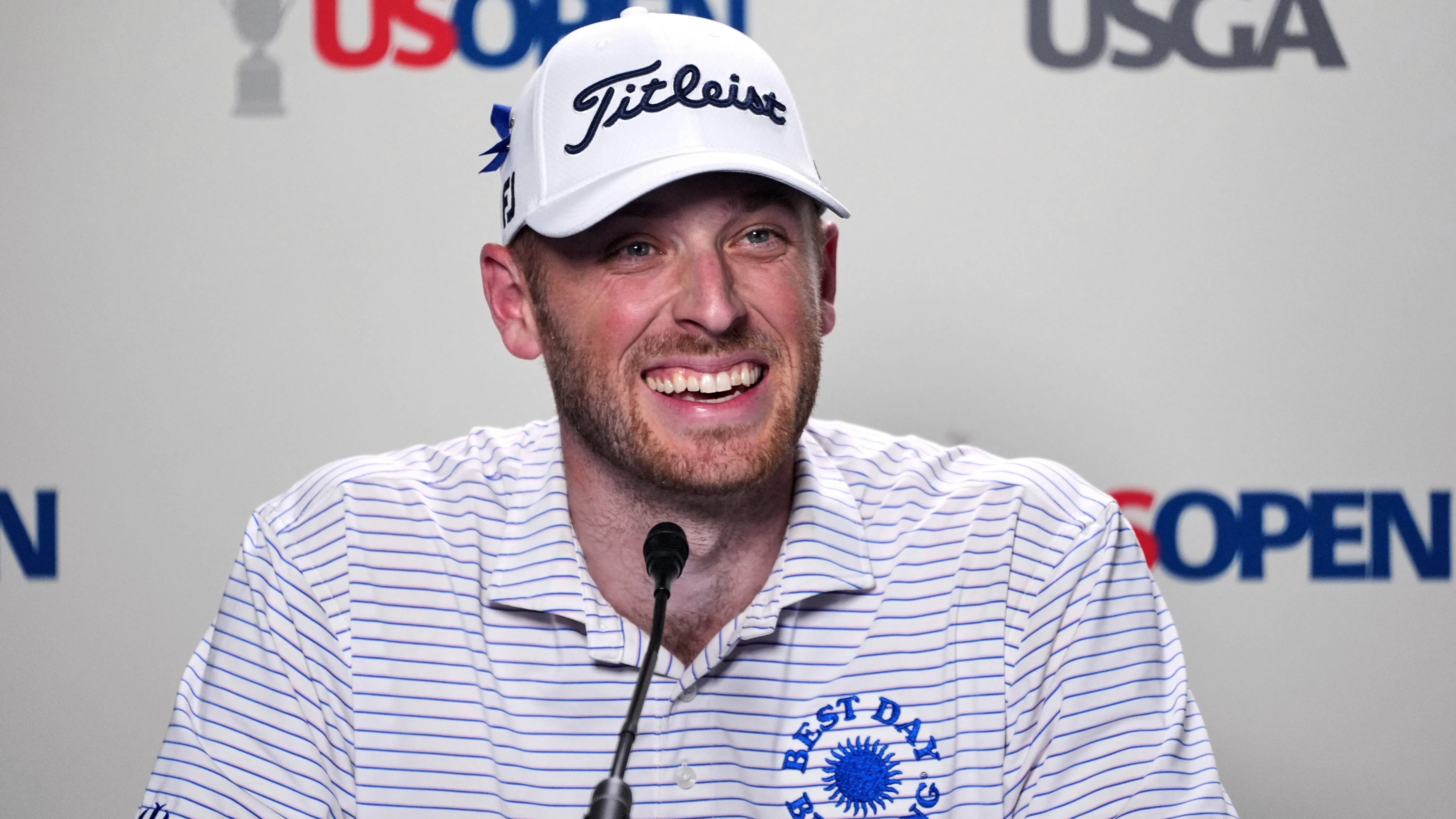 مات فوغت، طبيب أسنان، مبتسم خلال مؤتمر صحفي يتعلق بتأهله لبطولة أمريكا المفتوحة للجولف، مع خلفية تحمل شعار البطولة.