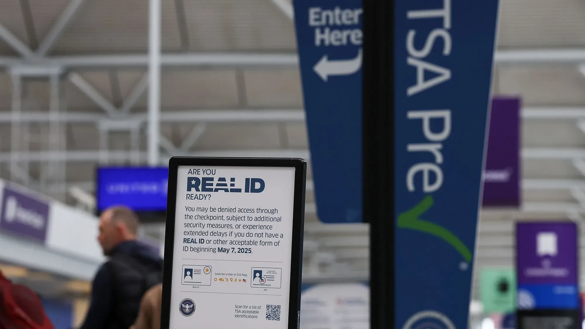 لافتة في مطار تحذر المسافرين حول متطلبات بطاقة الهوية الحقيقية، مع وجود إشارات لخدمات TSA Pre.