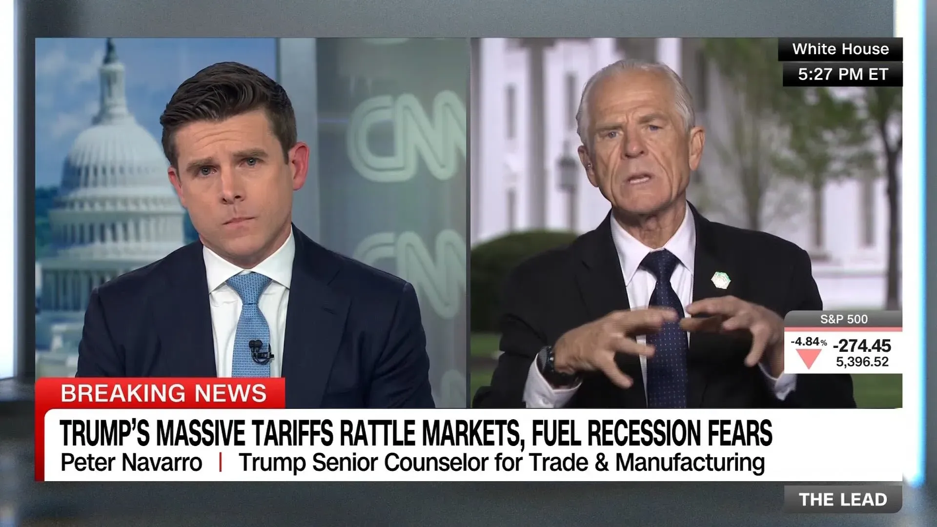 بيتر نافارو يتحدث في مقابلة تلفزيونية حول تأثير التعريفات الجمركية على الأسواق، بينما يراقب المراسل في خلفية البيت الأبيض.