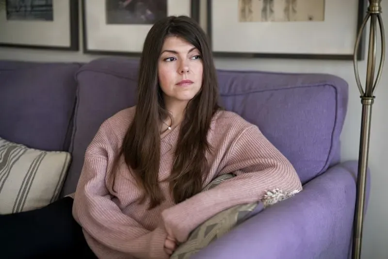 لارا، ناشطة في منظمة Feline Guardians، تجلس على أريكة وتبدو متأملة، تعبر عن قلقها بشأن انتشار تعذيب القطط عبر الإنترنت.