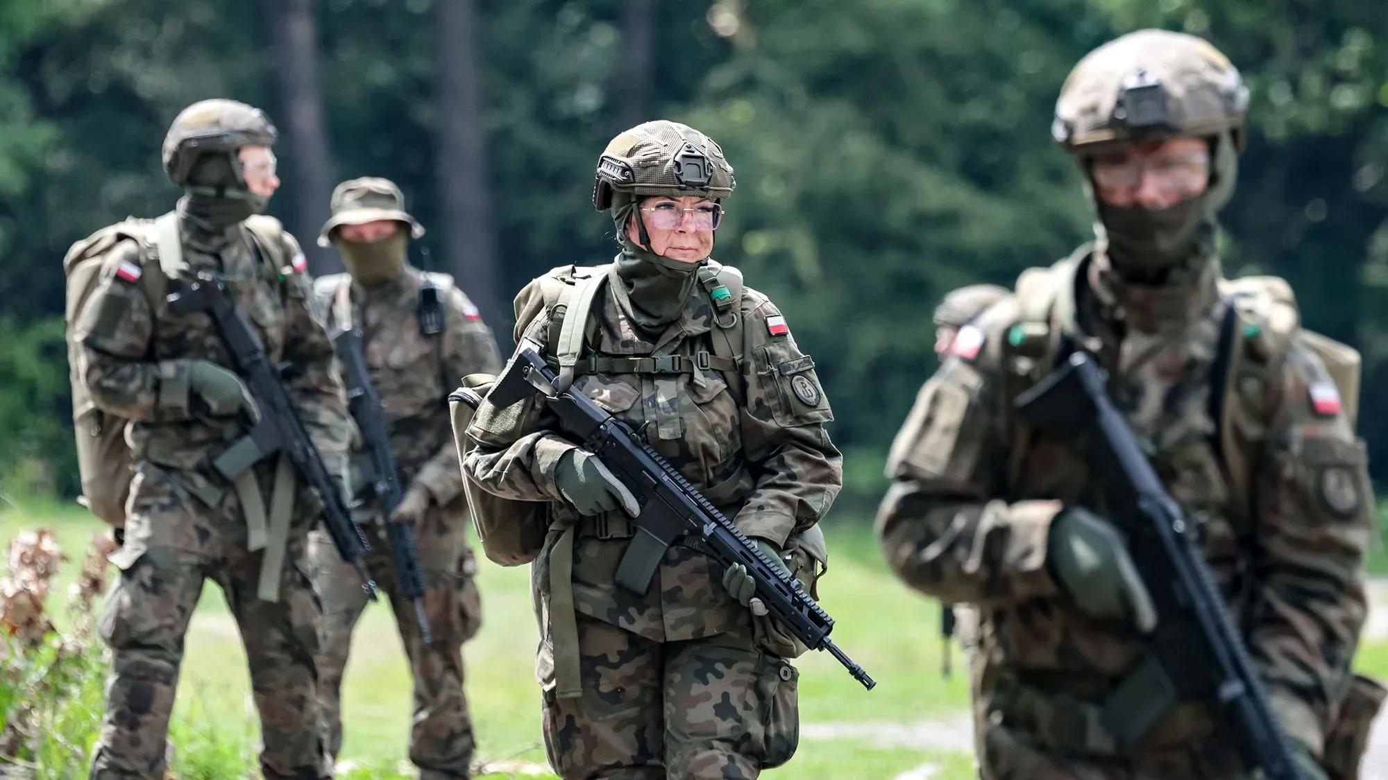 جنود من القوات المسلحة البولندية يرتدون زيًا عسكريًا كاملاً ويستعدون في منطقة مفتوحة، في سياق مناقشات حول التهديدات الأمنية في أوروبا.