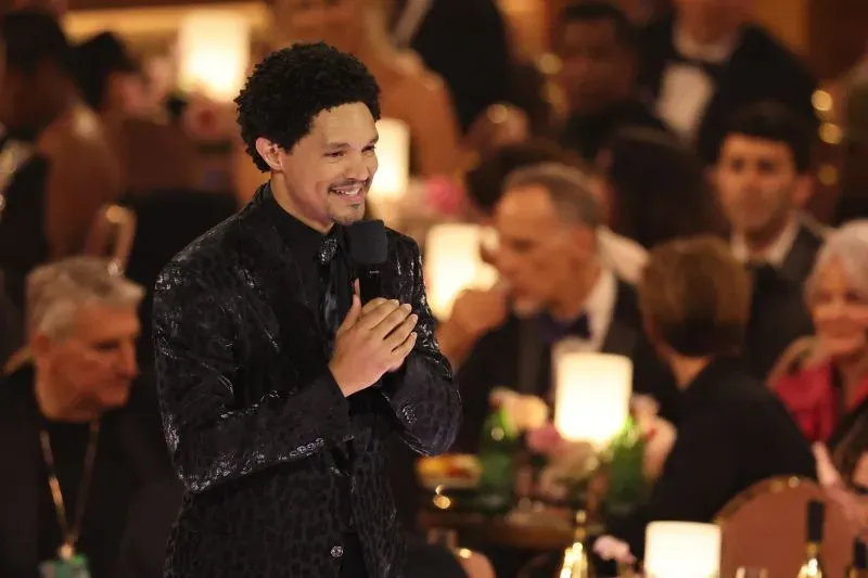 تريفور نوح يتحدث على المسرح خلال حفل توزيع جوائز، محاط بجمهور يتفاعل معه، في أجواء احتفالية رغم الظروف الصعبة.