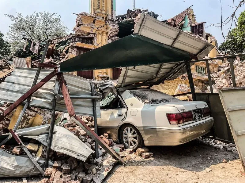 تظهر الصورة سيارة متضررة محاصرة تحت أنقاض مباني مدمرة في ساغاينغ، بعد الزلزال المدمر الذي أسفر عن دمار واسع النطاق.