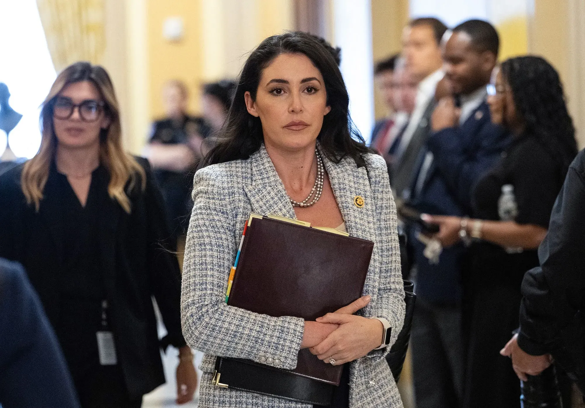 النائبة آنا بولينا لونا تحمل ملفًا وتظهر في ممرات الكونغرس، تعبر عن تصميمها على دفع تشريع لحظر تداول الأسهم للمشرعين.