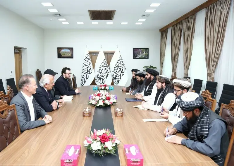 اجتماع بين مسؤولين من طالبان ومبعوثين أمريكيين، يتوسطهم طاولة مزينة بالورود، لمناقشة العلاقات الأمريكية الأفغانية.