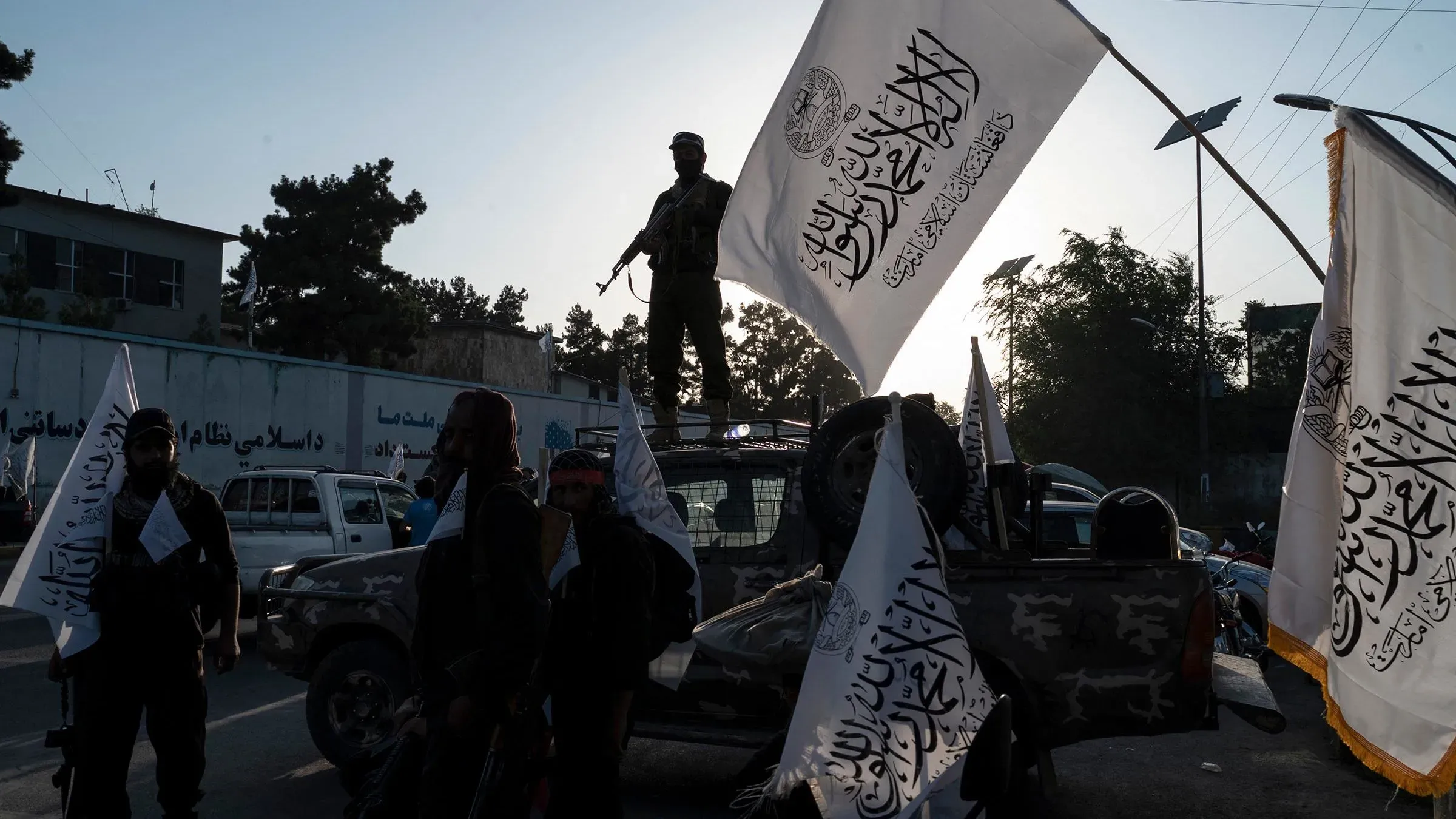 مقاتلو طالبان يحملون أعلام الحركة، مع أحدهم واقفًا على مركبة، في مشهد يظهر تواجدهم في كابول بعد استيلائهم على المدينة.