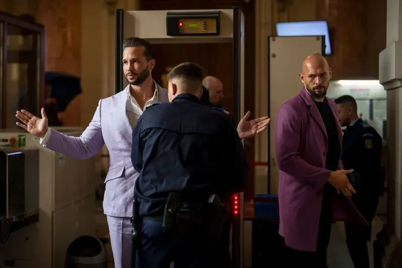 أندرو وتريستان تيت يتعرضان للتفتيش من قبل الشرطة في مطار، وسط تحقيقات حول الاتجار بالبشر والجرائم المنظمة.