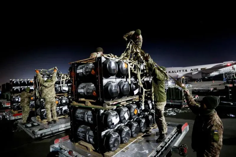 جنود يقومون بتحميل حاويات تحتوي على أسلحة وذخائر من طائرة شحن في مطار ليلي، في سياق دعم الأمن الأوروبي.