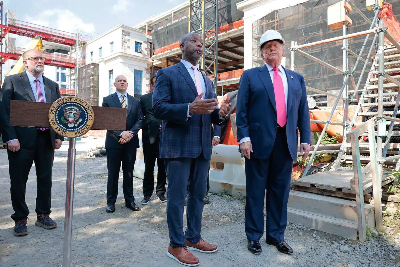 دونالد ترامب يتحدث مع مسؤولين آخرين أثناء جولة في موقع تجديدات مجلس الاحتياطي الفيدرالي، مع خلفية لمعدات البناء.