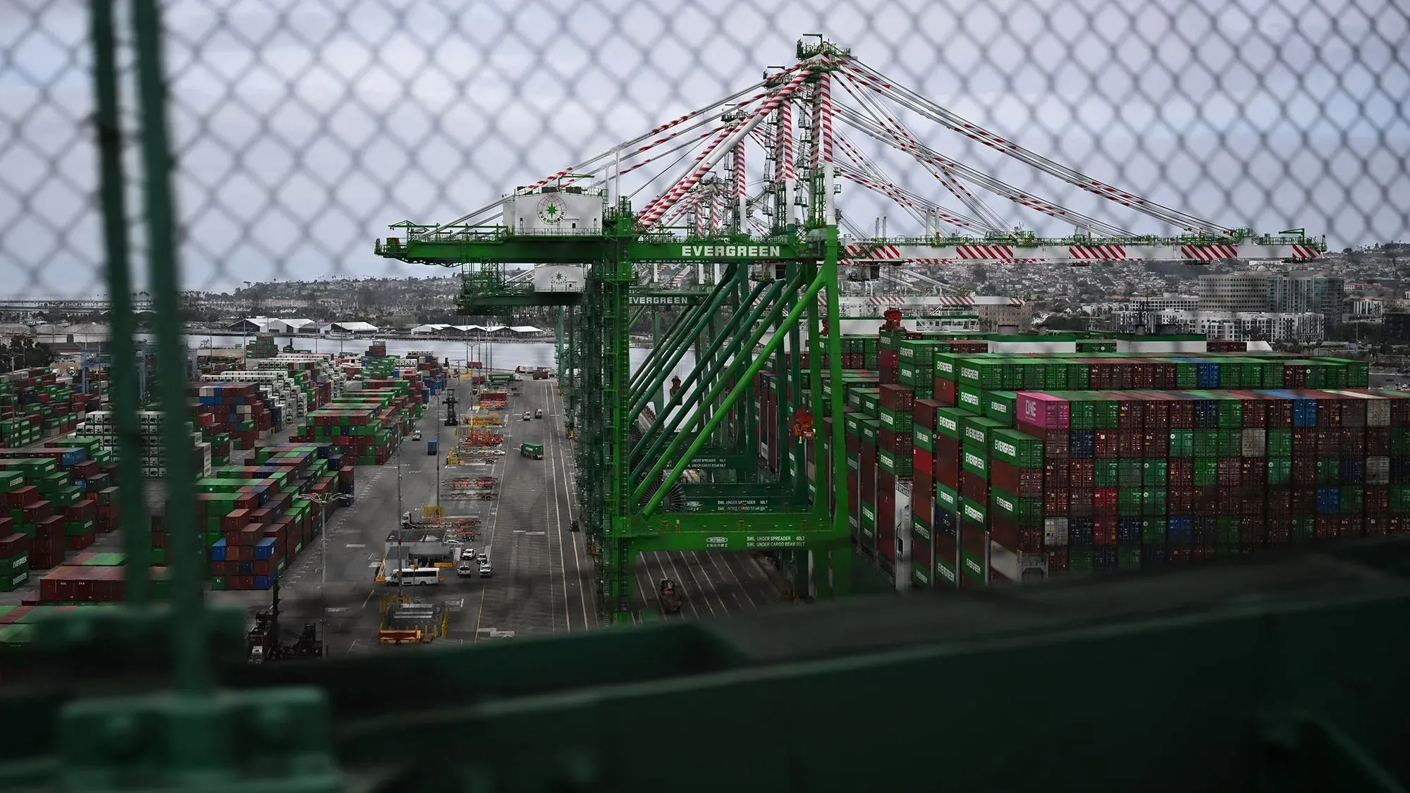 صورة لميناء مزدحم يظهر رافعات تحميل الحاويات الملونة، مما يعكس تأثير الرسوم الجمركية على التجارة الأمريكية والاقتصاد.