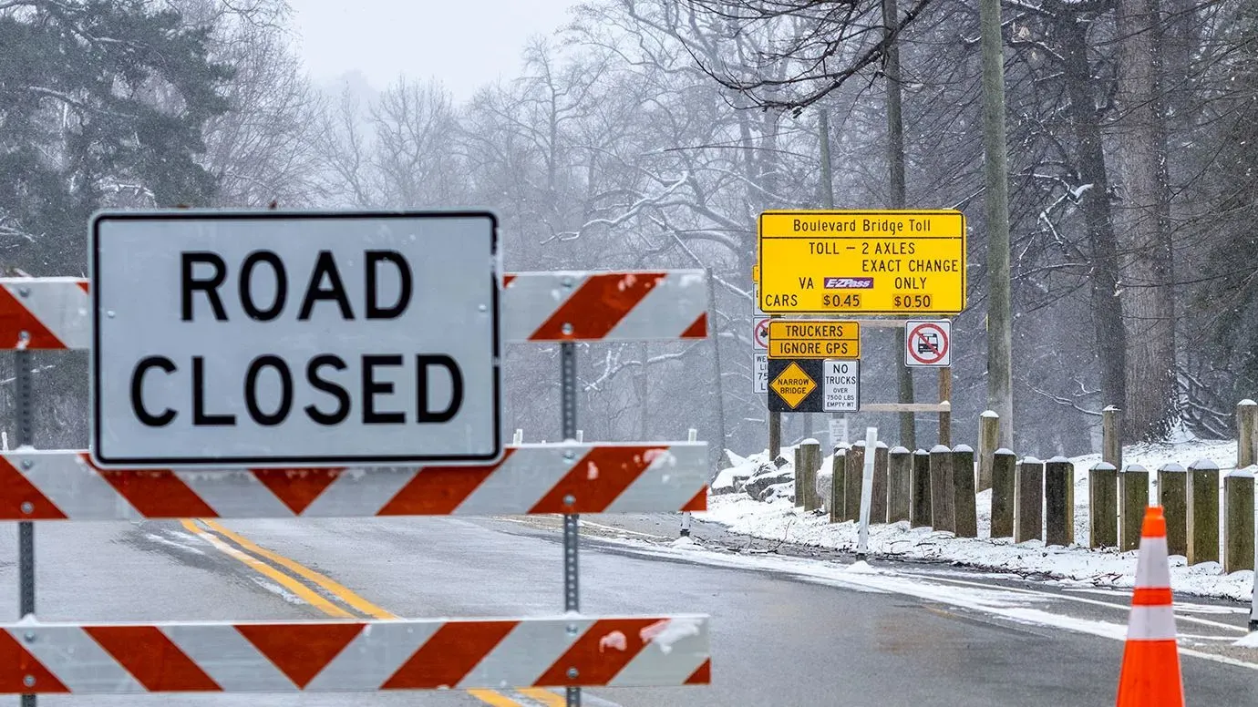 إغلاق الطريق بسبب العواصف الشتوية في فرجينيا، مع لافتة تحذيرية تشير إلى رسوم العبور، مما يعكس تأثير الكوارث الطبيعية على البنية التحتية.