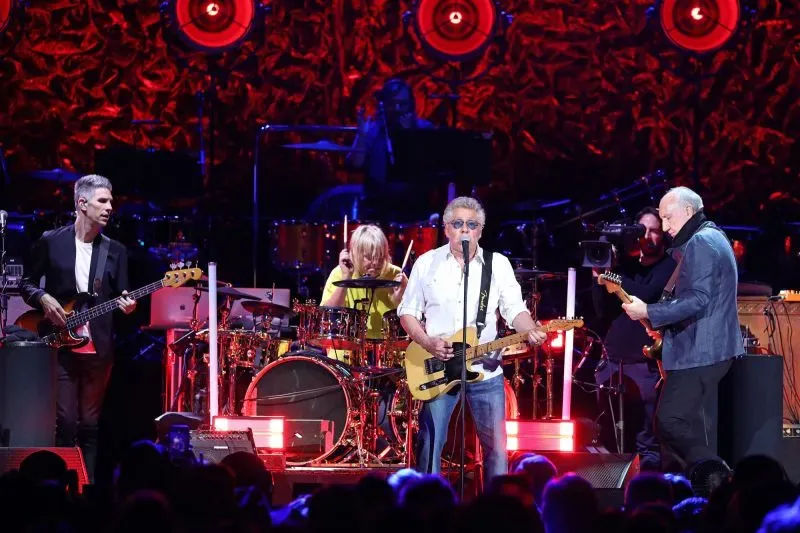 أعضاء فرقة The Who يؤدون على المسرح، مع التركيز على المغني روجر دالتري وعازف الجيتار بيت تاونشيند، وسط أجواء حماسية.