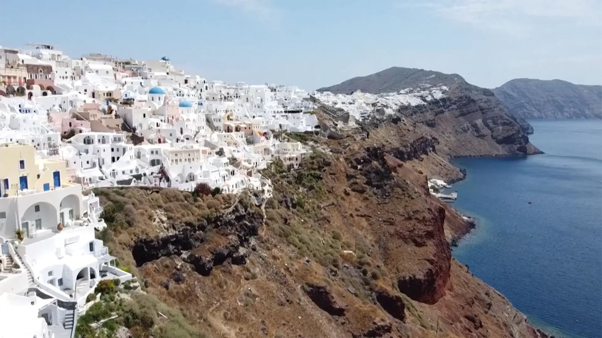 مشهد لجزر سانتوريني الشهيرة، حيث تظهر المنازل البيضاء على المنحدرات مع البحر الأزرق، وسط أجواء من القلق بسبب النشاط الزلزالي المتزايد.