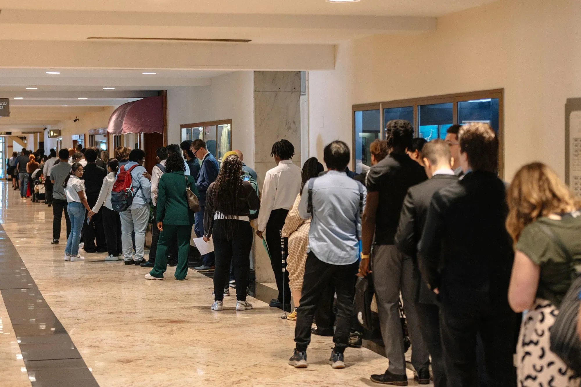 طابور طويل من الباحثين عن عمل في ممر، يعكس تحديات سوق العمل الحالي في الولايات المتحدة وقلة الفرص المتاحة.