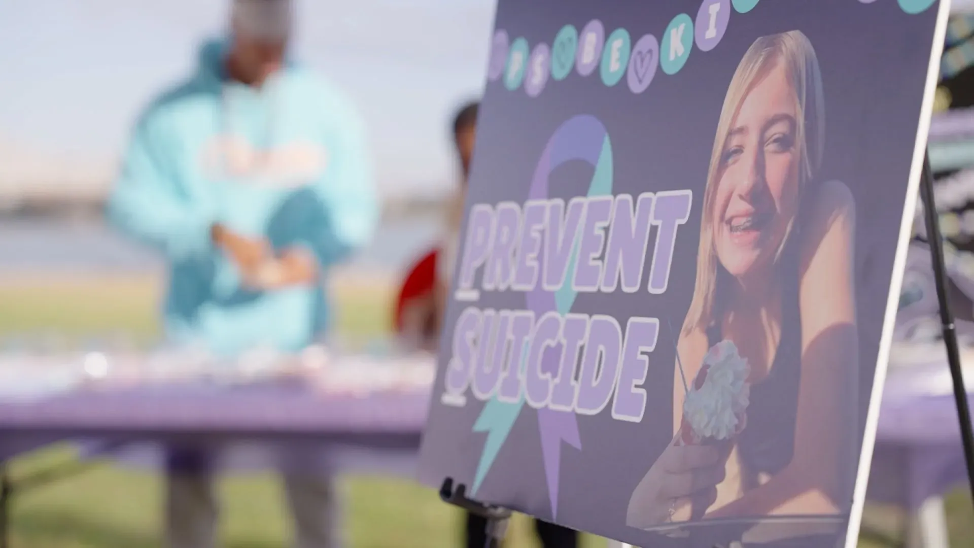 لافتة تظهر عبارة "منع الانتحار" مع صورة لفتاة مبتسمة، في حدث يهدف لزيادة الوعي حول الصحة النفسية والوقاية من الانتحار.