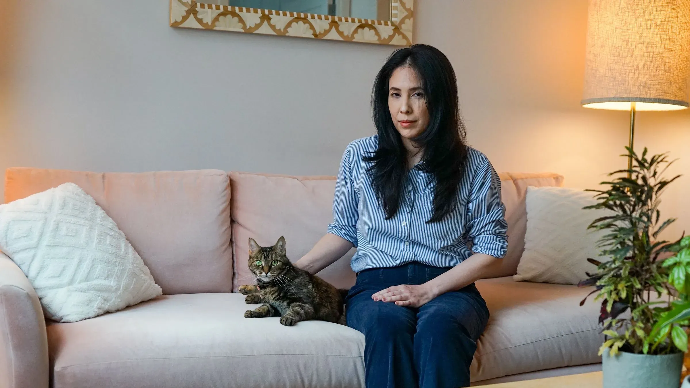 سوفيا باسان تجلس على أريكة مع قطتها، تعبر عن معاناتها من الألم بعد استئصال الثدي، مما يسلط الضوء على تحديات متلازمة الألم ما بعد الاستئصال.