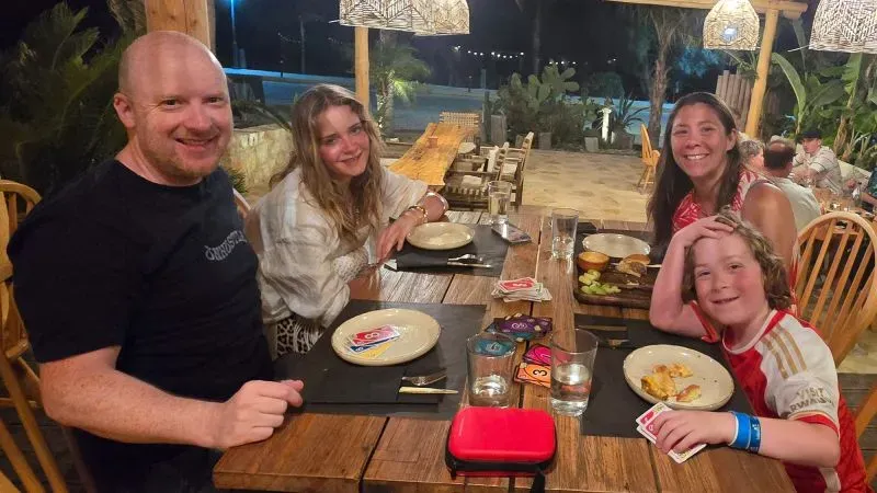 مجموعة من الأشخاص يجلسون حول طاولة في مطعم، يتناولون الطعام ويستمتعون بوقتهم معاً، في أجواء مريحة ومبهجة.