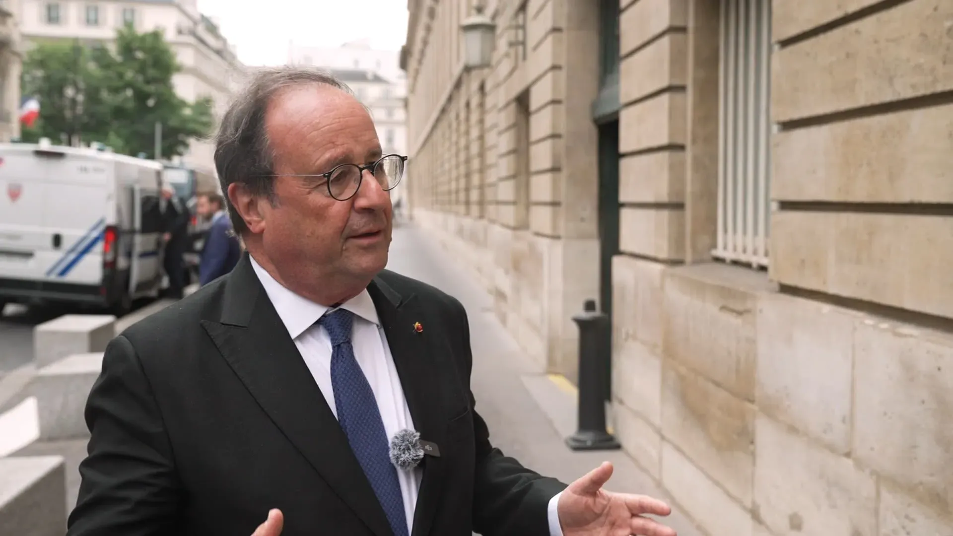 رئيس فرنسا السابق فرانسوا هولاند يتحدث في الشارع، مع التركيز على تعبيراته وملابسه الرسمية، في سياق تعزيز التعاون الأوروبي.
