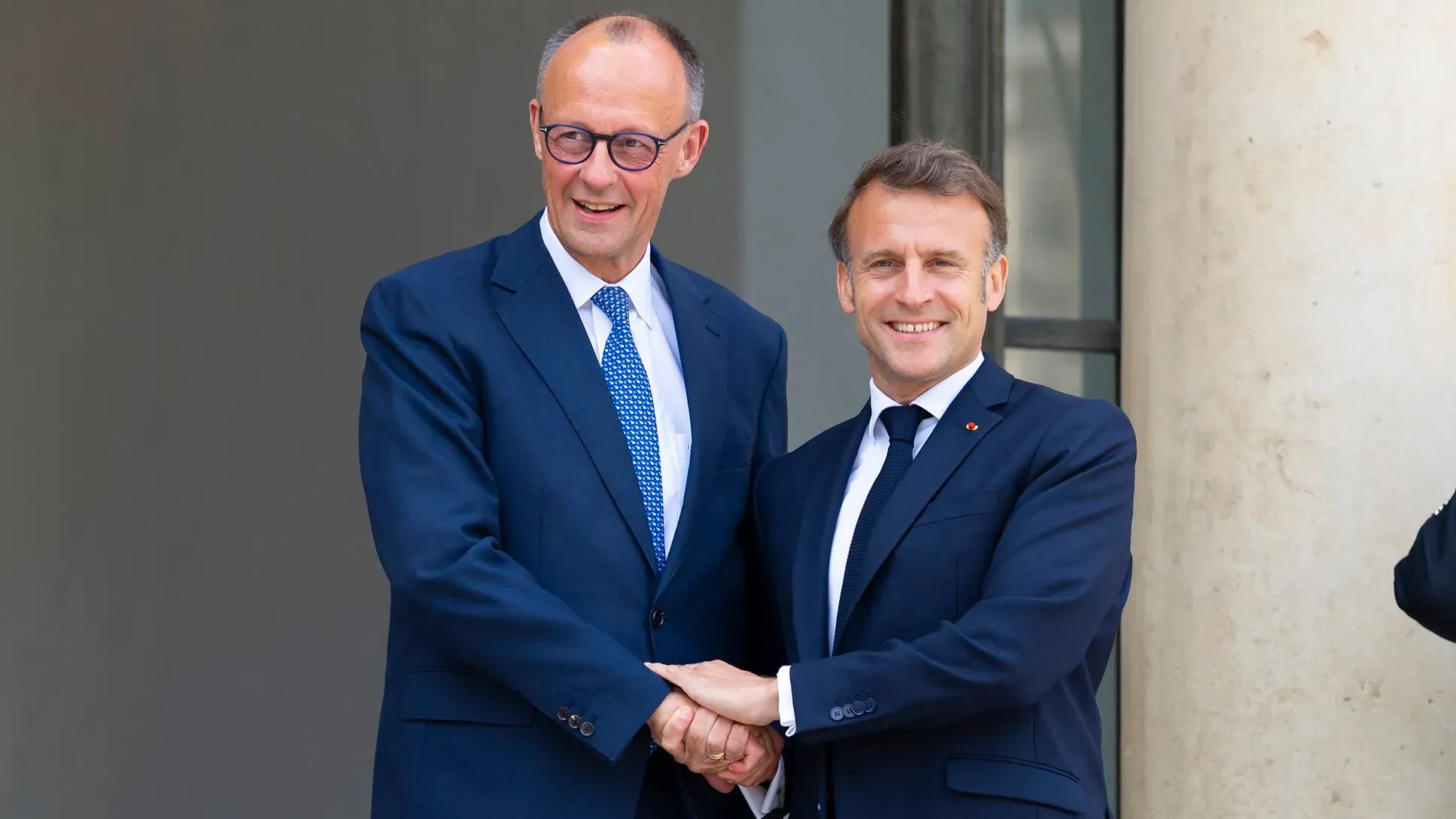 ماكرون وميرتس يتصافحان في قصر الإليزيه، رمز لتجديد التحالف الفرنسي الألماني، مع التركيز على الأمن الأوروبي وأوكرانيا.