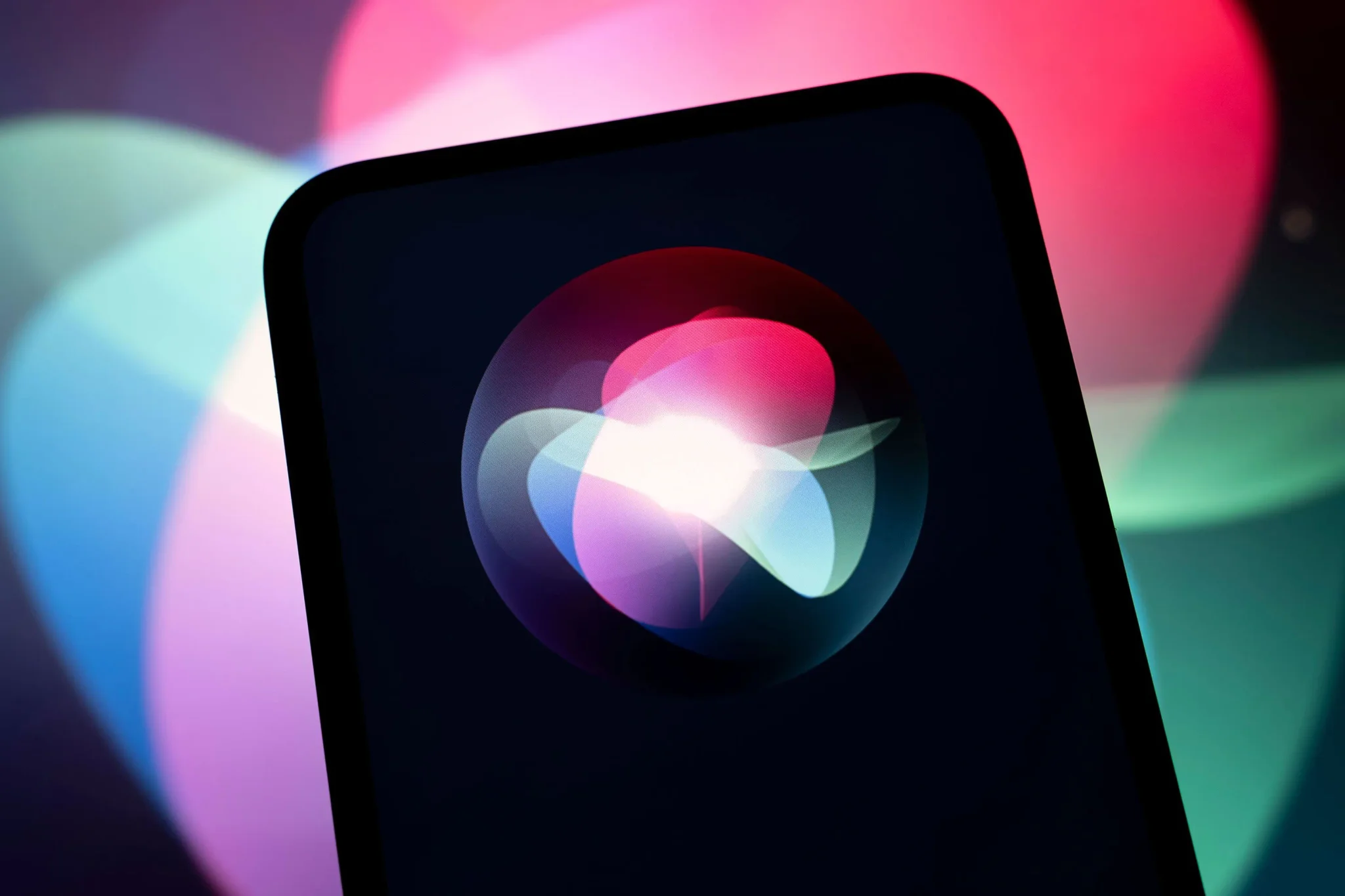 شاشة هاتف تعرض شعار Siri المتحرك، مع خلفية ملونة تعكس تحديث iOS 17 وتحسينات مساعد أبل الصوتي الذكي في إنجاز المهام.