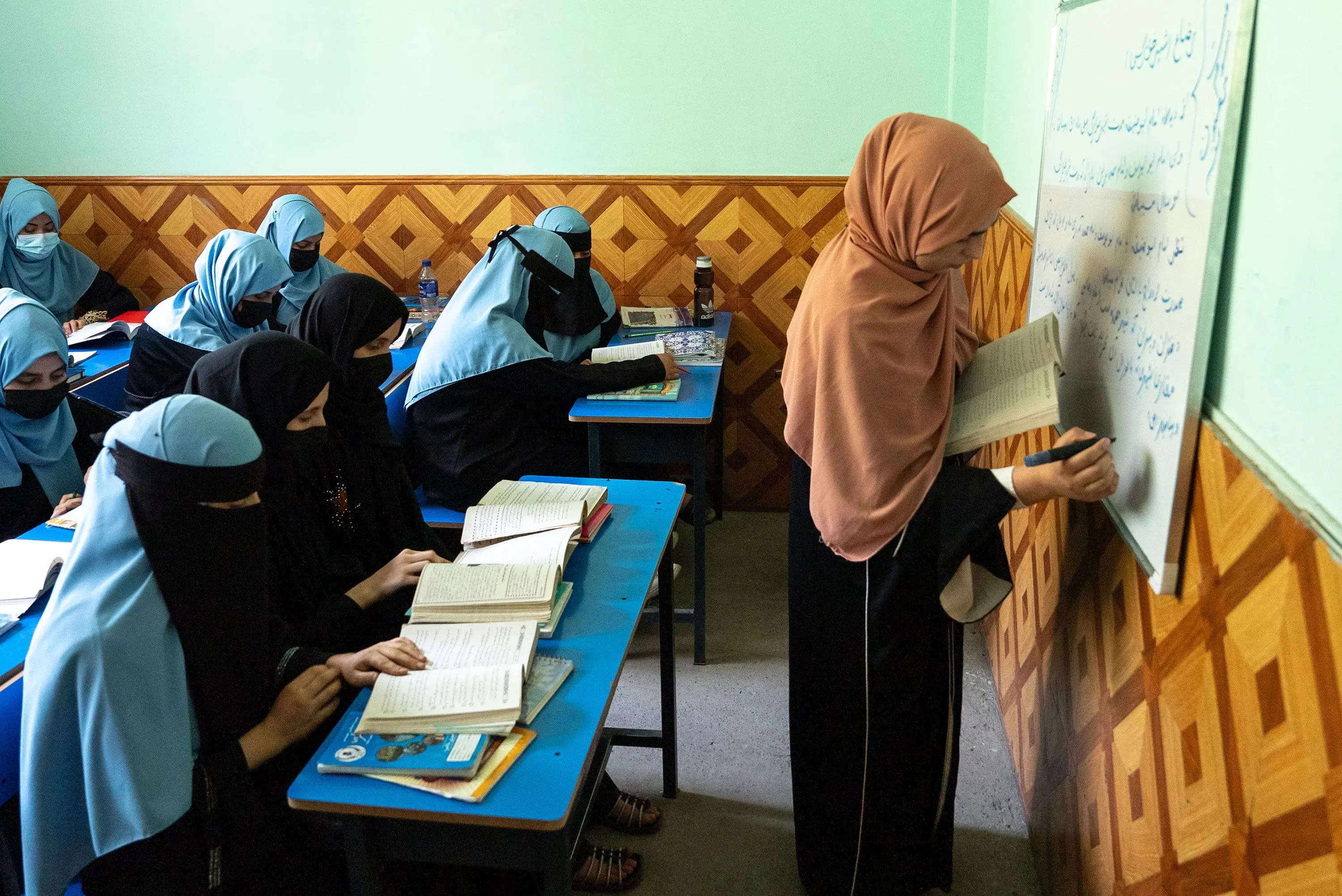 فتيات يرتدين الحجاب داخل مدرسة دينية في كابول، يدرسن ويتعلمن تحت إشراف معلمة، وسط أجواء تعليمية تركز على القيم الإسلامية.