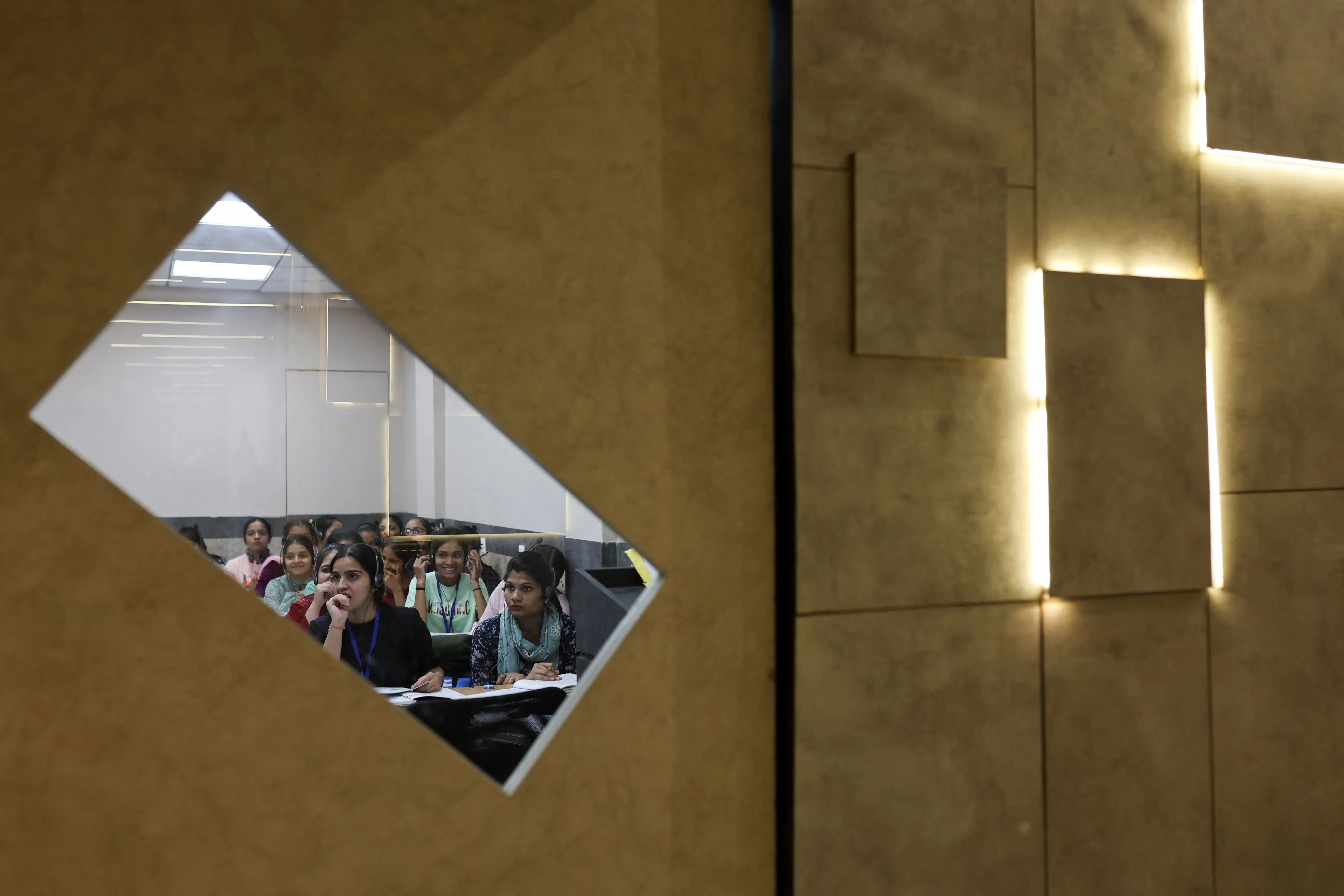 مجموعة من الطالبات في فصل دراسي يتابعن الدروس بتركيز، تعكس الصورة التحديات التي تواجه الطلاب الهنود في الحصول على تأشيرات للدراسة في الولايات المتحدة.