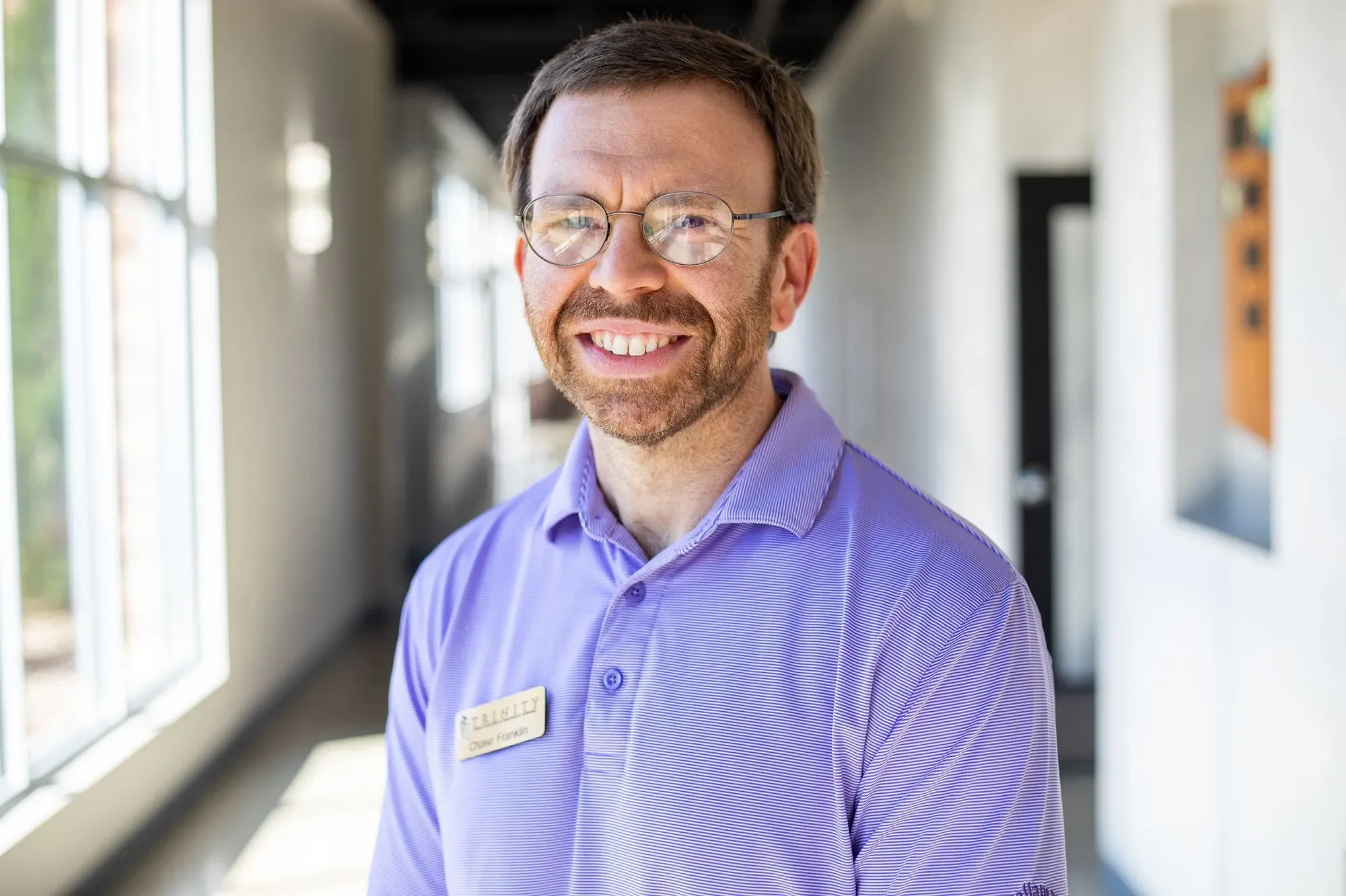 تشايس فرانكلين مبتسم، يرتدي قميصًا بنفسجيًا، يقف في ممر مضاء. يعكس وجهه القلق بسبب الإغلاق الحكومي وتأثيره على خطط شراء منزله.