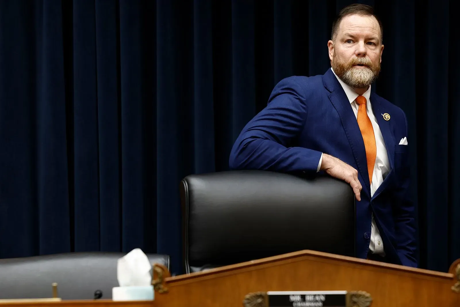 النائب تيم بورشيت يقف بجانب مقعده في الكونغرس، معبرًا عن مخاوفه بشأن تخفيضات الميزانية الحكومية وتأثيرها على الحكومة الفيدرالية.