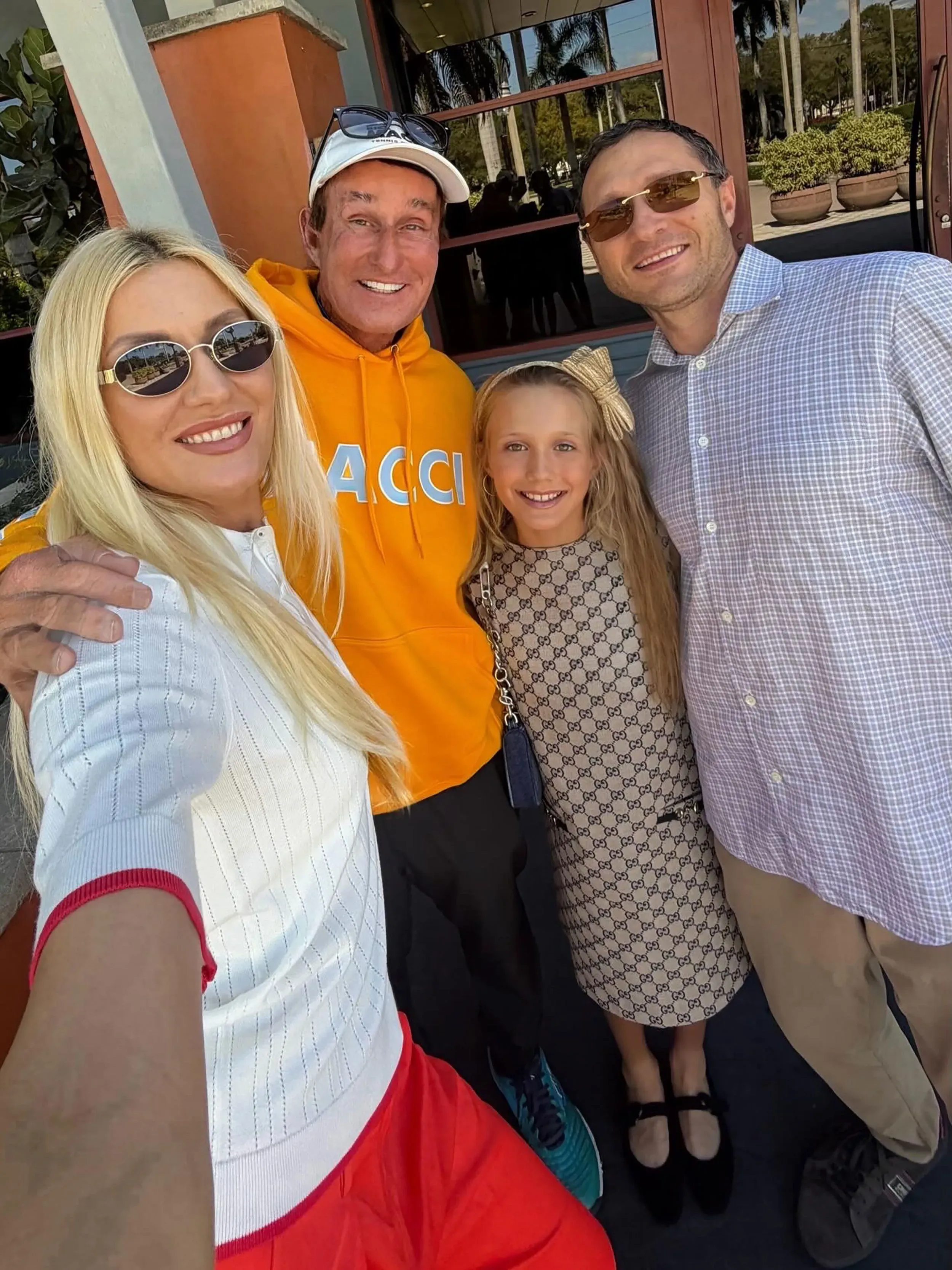 صورة عائلية تضم فلادا هرانشار، لاعبة التنس الشابة، مع مدربها ريك ماتشي ووالديها، في مكان مفتوح مع أشجار في الخلفية.