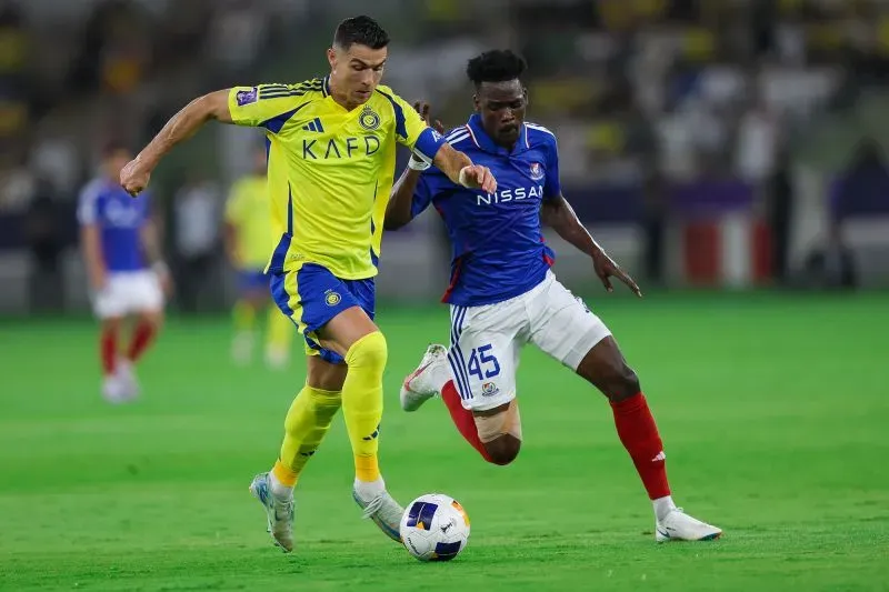 رونالدو في مباراة مع النصر، يتجاوز لاعب الفتح، مسجلاً هدفه رقم 25 في الدوري السعودي، وسط أجواء تنافسية.